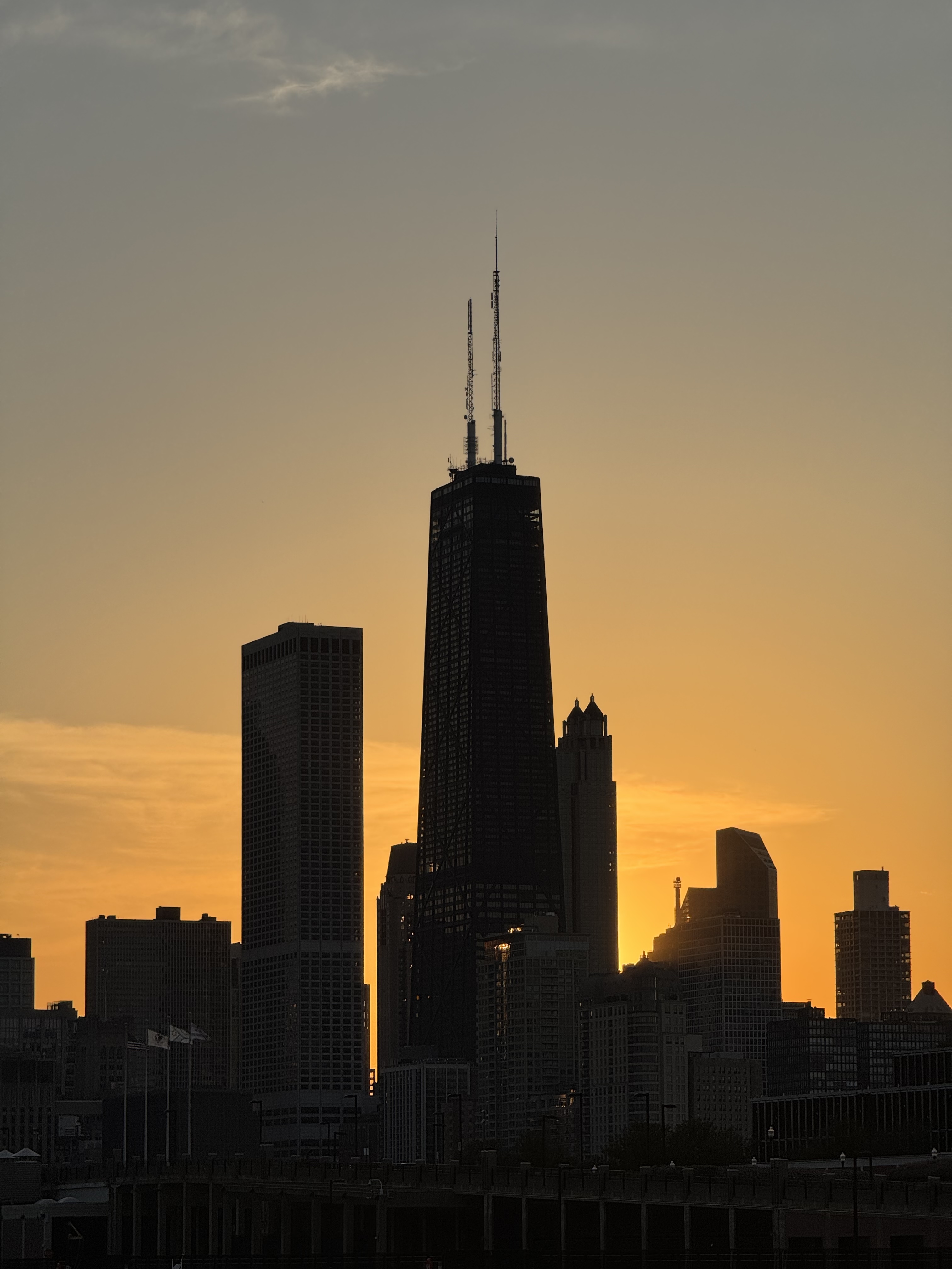 Chicago skyline at sunset with the John Hancock Center silhouetted against an orange sky