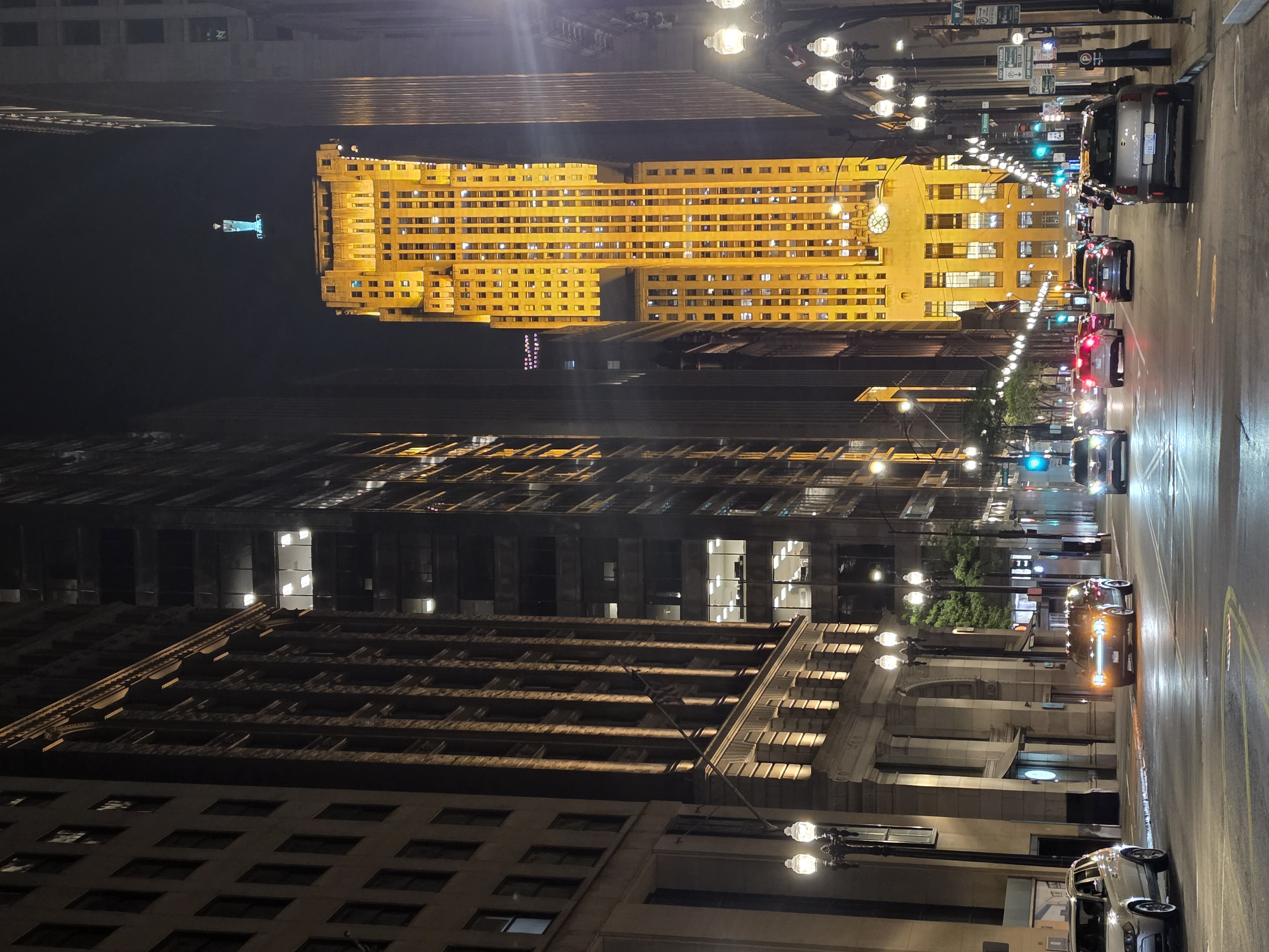Chicago Board of Trade Building glowing gold at the end of a rain-wet LaSalle Street at night, L train tracks overhead