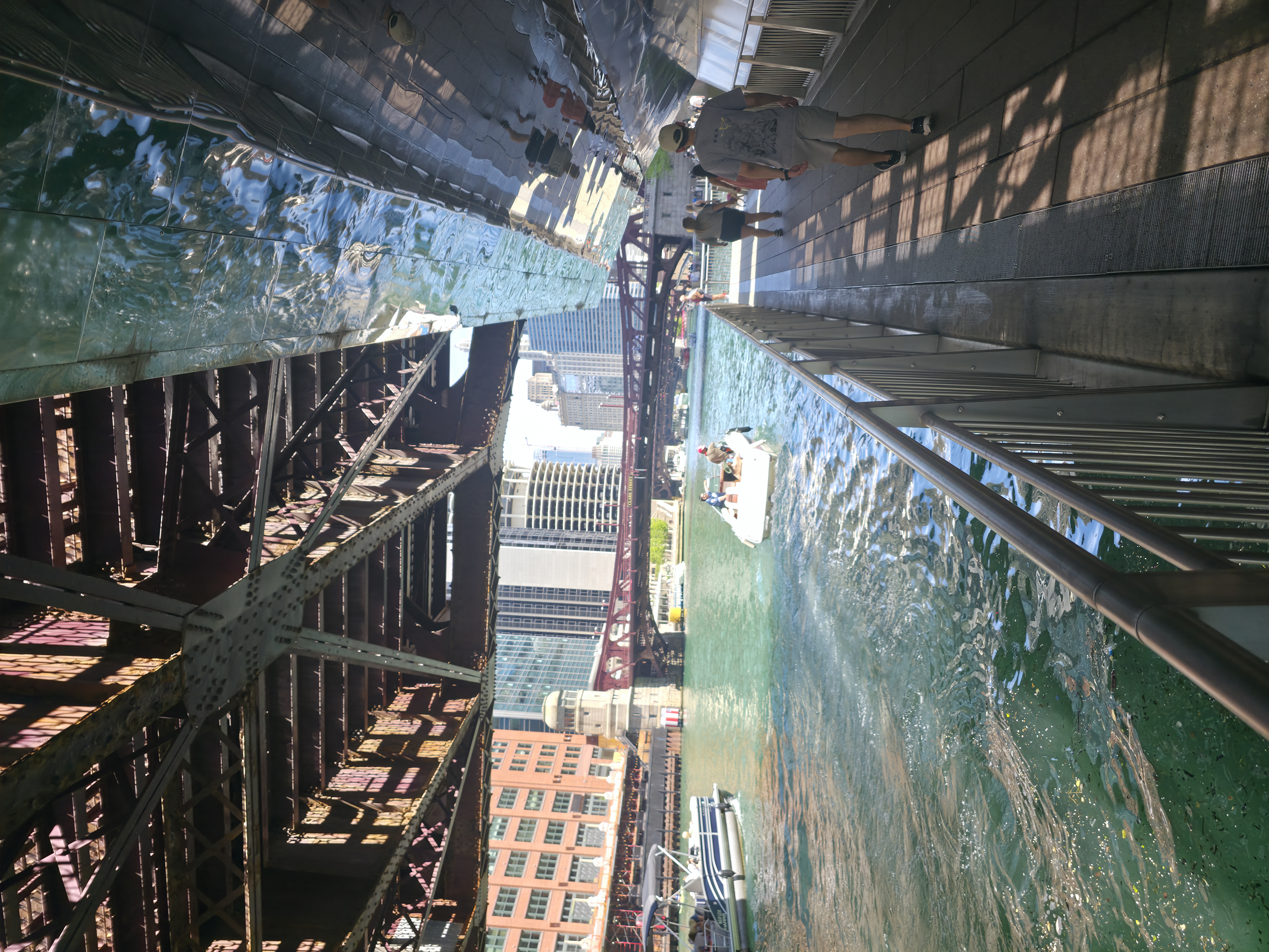View straight down through iron bridge girders to the green Chicago River and buildings below