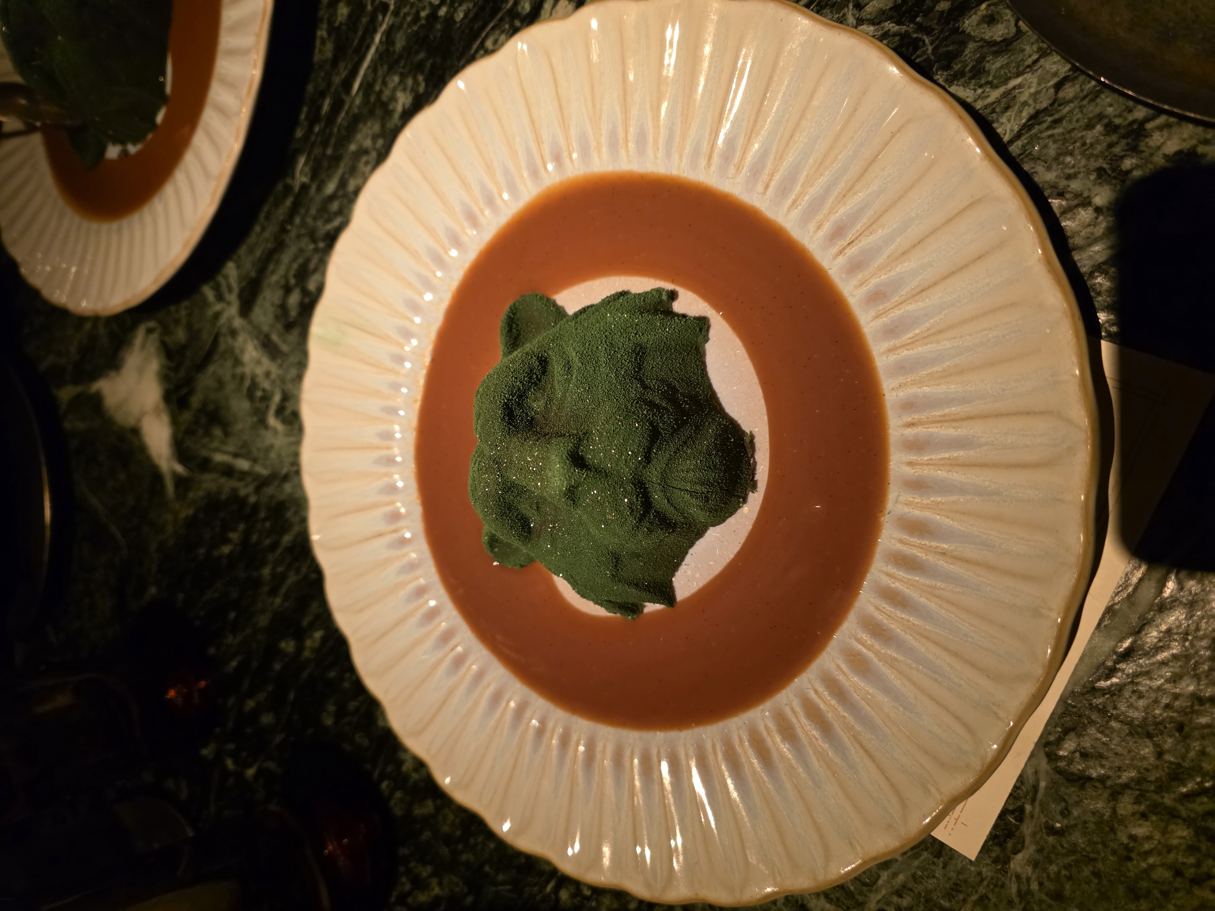 Crying Tiger dessert: dark green ice cream in the centre of a ring of brown sauce on a white fluted plate