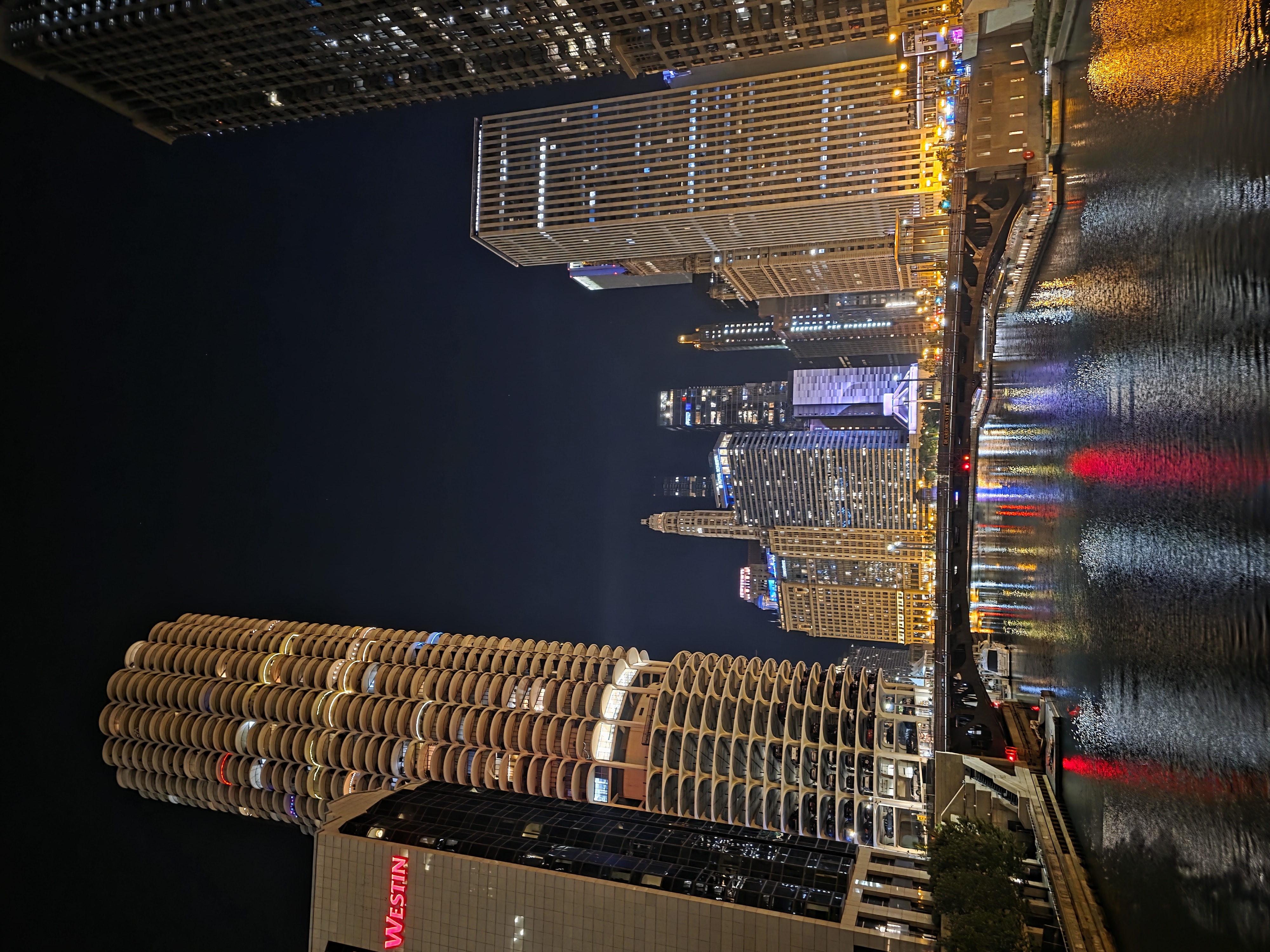 Marina City's circular towers lit up at night with their lights reflecting in the Chicago River below